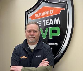 A man standing in front of the SERVPRO one team sign