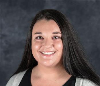 Woman posing for a professional headshot in front of a grey background.