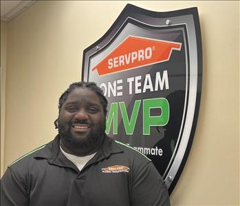A man standing in front of the SERVPRO one team sign