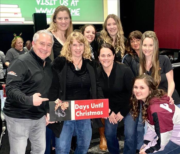 9 people standing together after sponsoring and helping out a local non-profit at Trivia Night