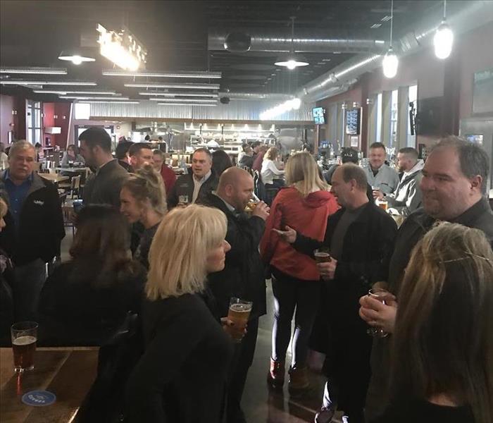 A group of people standing around talking and networking 