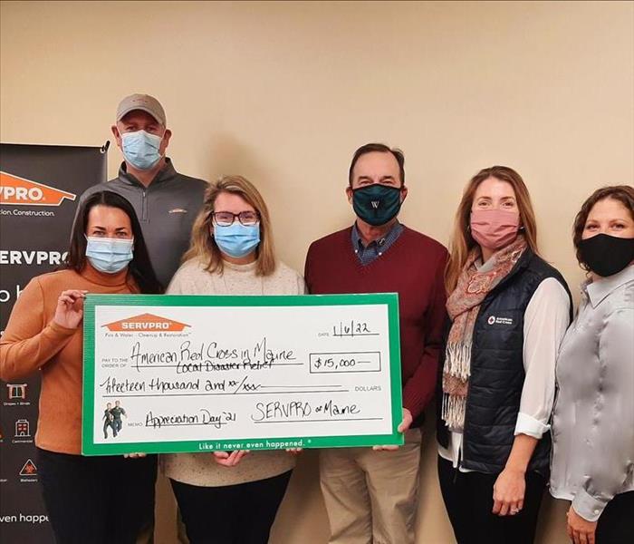 2 men and 4 women holding large check donation 