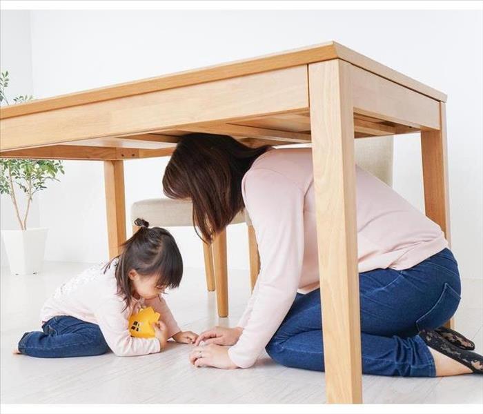 A parent and child huddling under a table